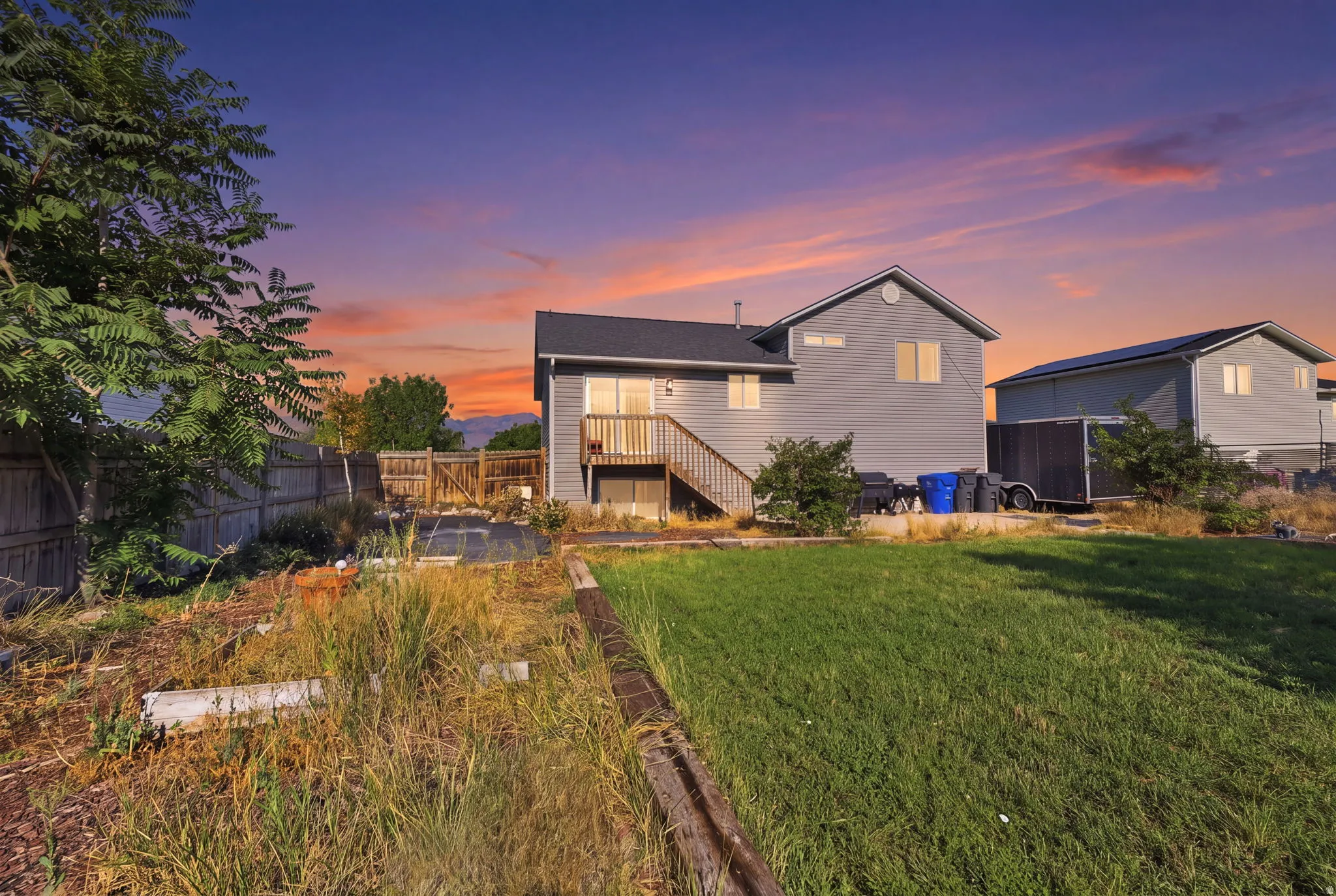 Modern two-story residence with board-and-batten exterior siding and gabled roofline, illuminated by interior lighting