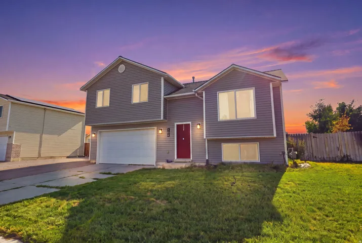 Modern two-story home featuring a clean siding exterior with a covered front entry and red accent door