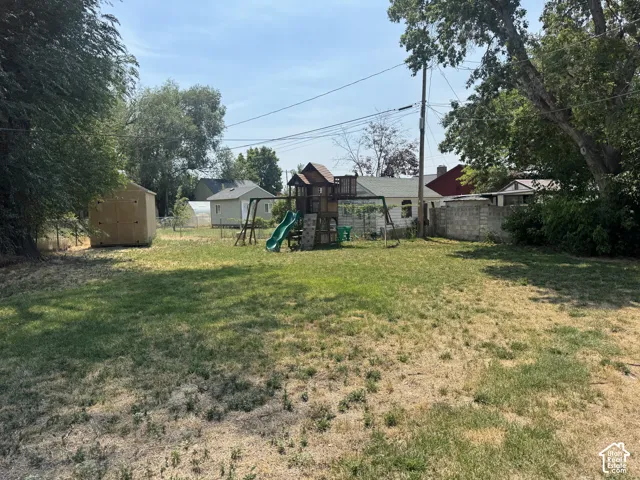 Expansive yard space featuring a storage shed and mature trees