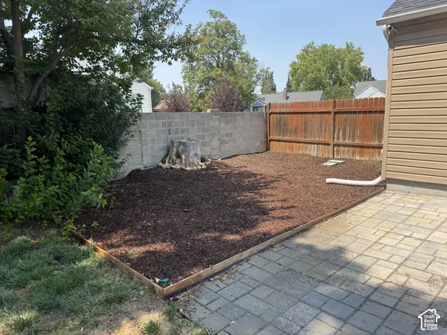 Paved patio area, wood fencing, concrete block wall, and rich ground covering