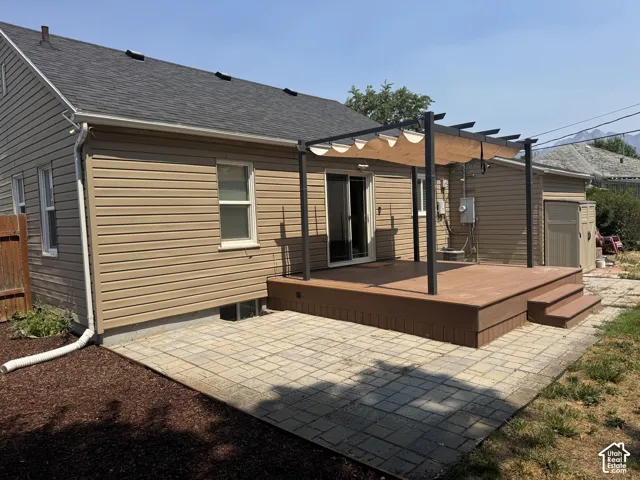 Expansive composite deck with a retractable shade pergola, leading to a paver patio