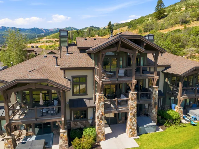 Architectural masterpiece featuring a two-story stone and timber-frame design with multiple pitched rooflines and expansive covered porches