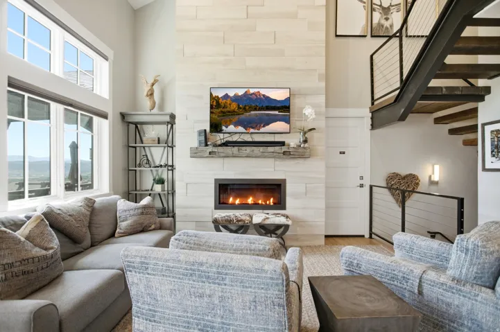 Living area featuring a floor-to-ceiling tiled fireplace surround, a built-in linear fireplace, a floating wood-finish mantel, and large picture windows