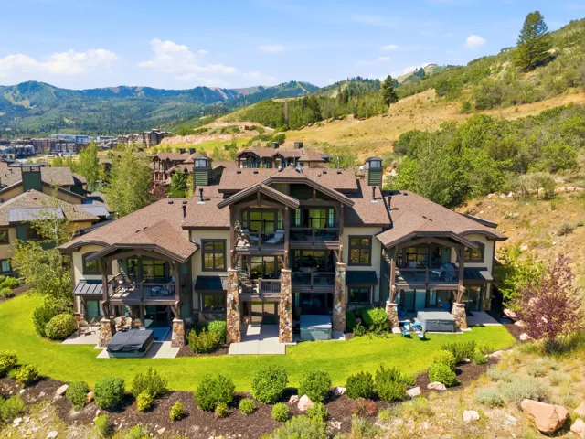 Striking contemporary mountain estate featuring a multi-level architectural design with stone and timber accents, expansive windows, and bronze-toned metal roofing