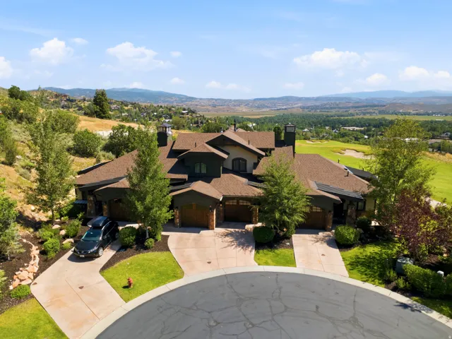 Expansive residential estate showcasing a striking contemporary architectural design with dark exterior finishes, multiple peaked rooflines, and prominent chimney elements