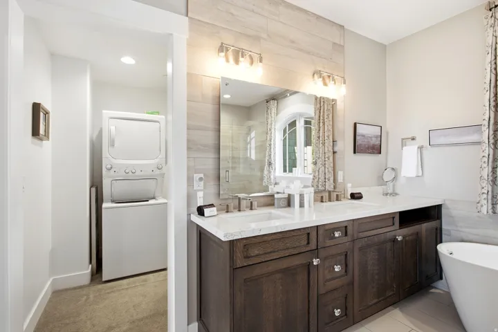 Spa-inspired primary bathroom featuring a dark wood double-vanity with white quartz countertops, polished nickel fixtures, and an abundance of storage