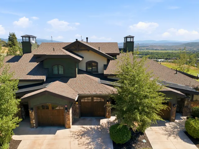 Spacious multi-level residence with a brown shingle roof, green siding, and stone accents