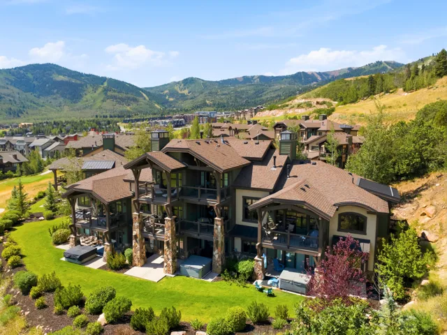 Striking contemporary estate showcasing a dramatic multi-level stone and stucco exterior with expansive curved rooflines and architectural detailing