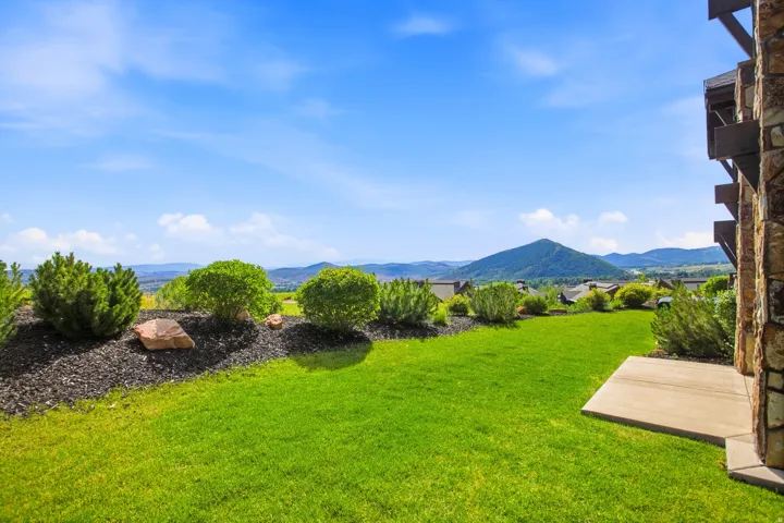 Expansive manicured lawn with lush green grounds and mature landscaping featuring strategically placed shrubs and trees