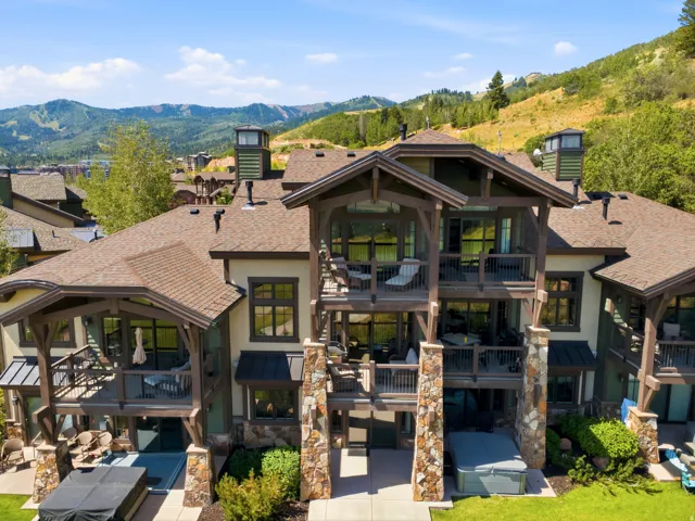 Multi-level property with expansive outdoor living spaces, mountain backdrop, and individual covered patios