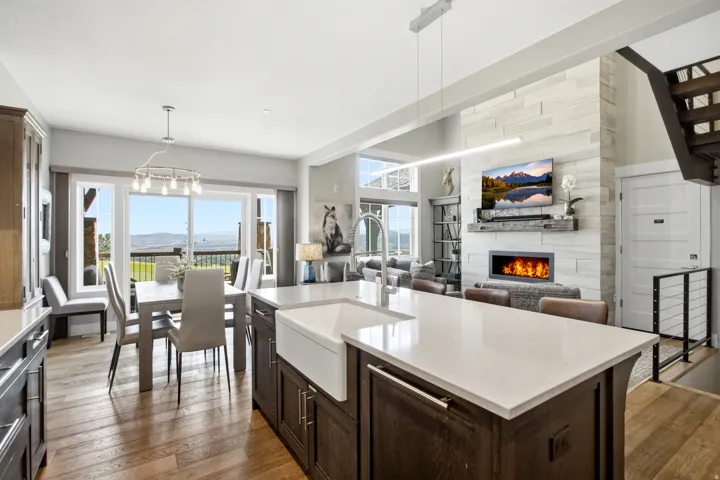 Gourmet kitchen featuring a large center island with white quartz countertop and apron-front sink, dark wood cabinetry, stainless steel appliances, and pendant lighting