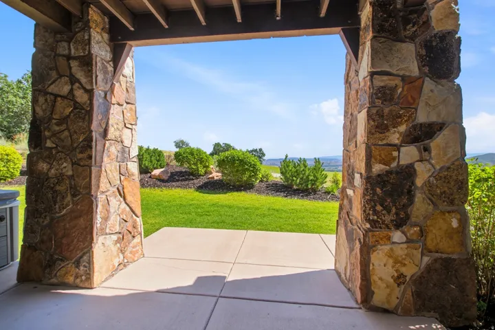 Rustic stone archway framing manicured grounds with mature landscaping, open lawn space, and distant landscape backdrop