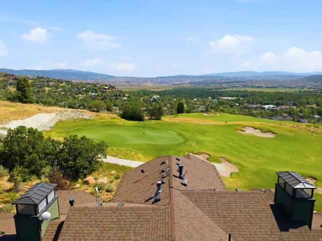 Stunning golf course views frame this elevated residence, showcasing a professionally maintained putting green with strategic sand bunkers, manicured fairways, and mature landscaping