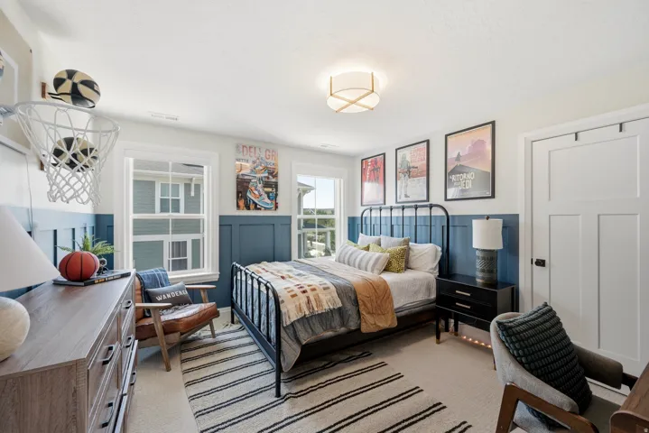 Bright bedroom featuring a black metal bed frame, wood-finish flooring, and geometric area rug