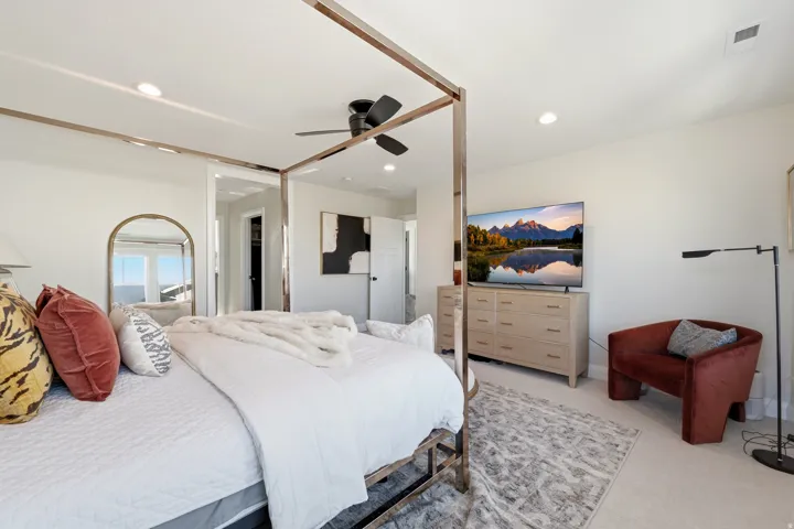 Spacious bedroom featuring light neutral wall tones, recessed lighting, and a ceiling fan