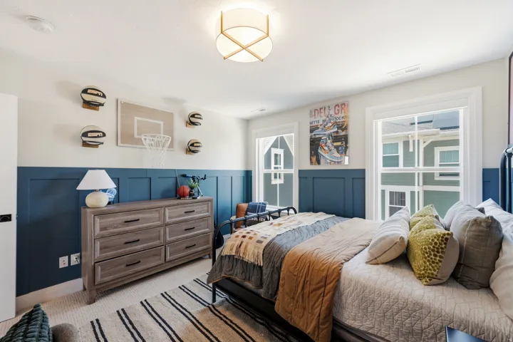 Room featuring board and batten wall paneling, a ceiling-mounted light fixture, two windows with white trim, and light-colored carpeting