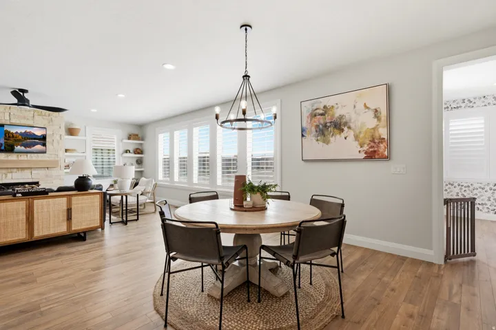 Bright dining area showcasing a round wood table, four upholstered chairs, and a striking geometric pendant light fixture