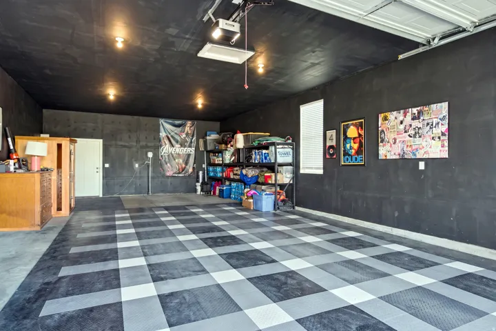 Spacious garage featuring dark walls and ceiling, checkerboard pattern floor tiles, and recessed lighting