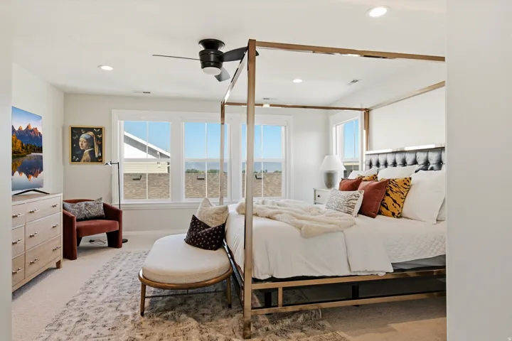 Carpeted room featuring a ceiling fan with integrated lighting, recessed lighting, and multiple windows