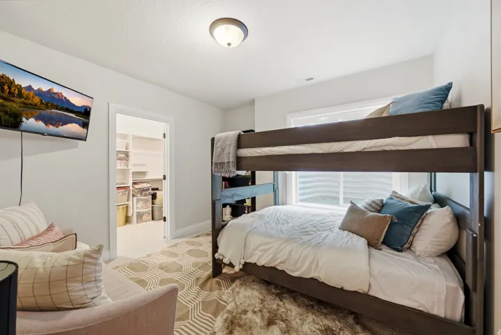 Bedroom featuring light gray walls, a built-in bunk bed frame, and a walk-in closet with extensive shelving