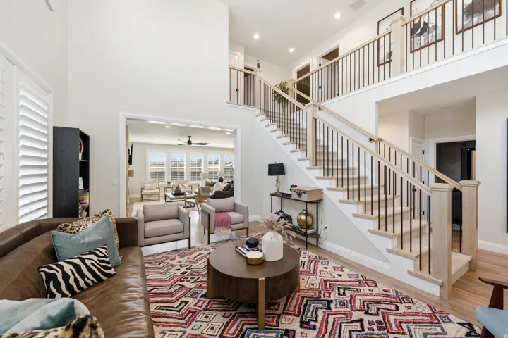 Two-story living area featuring a prominent staircase with wood-finish handrails and black metal spindles
