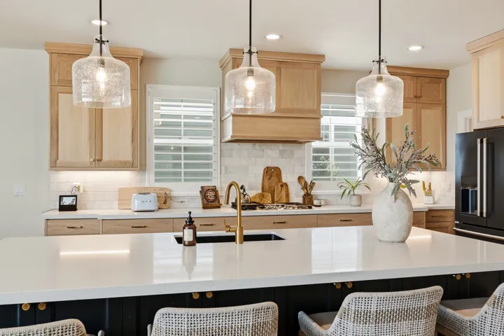 Kitchen island with a white solid surface countertop and integrated lighting, featuring three seeded glass pendant lights
