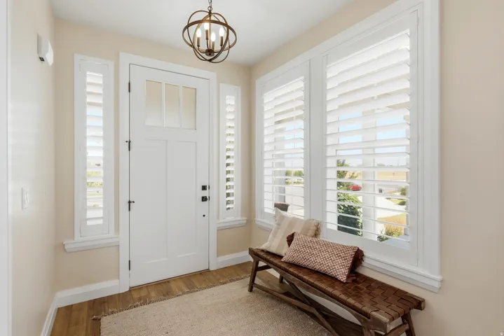 Entryway featuring a white paneled door with glass inserts, flanked by side windows with white plantation shutters