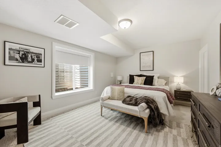 Well-appointed bedroom featuring a recessed window with blinds, ceiling-mounted light fixture, and light-colored walls