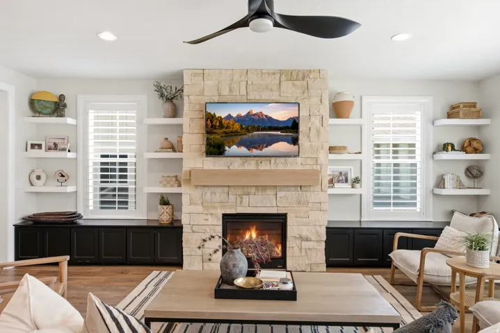 Stone-clad fireplace with a wood mantel and built-in shelving