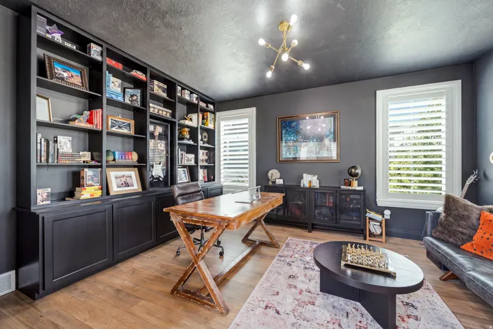 Custom built-in shelving with lower cabinetry frames the wall, complemented by light wood-finish flooring