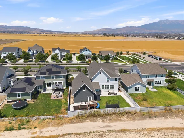 Elevated aerial perspective showcasing this contemporary home featuring a dark composite roof, multi-level architecture with white and charcoal exterior finishes, and manicured landscaping with mature plantings