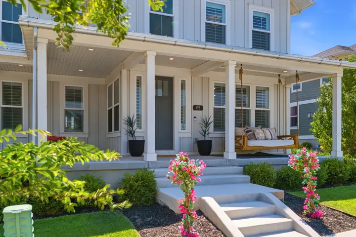 Charming farmhouse-style residence showcasing a welcoming front porch with white columns, recessed ceiling, and integrated lighting