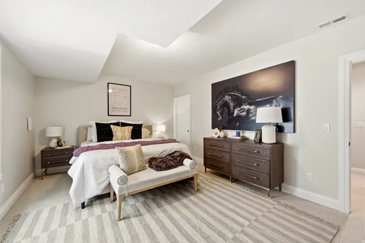 Spacious primary bedroom featuring vaulted ceilings, wood-finish flooring with striped patterning, and abundant natural light