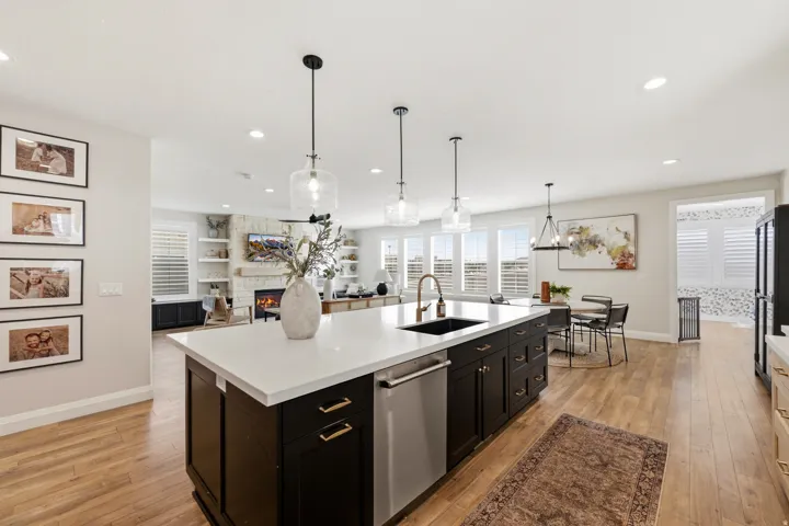 Expansive kitchen island with a white countertop, undermount sink, and pendant lighting