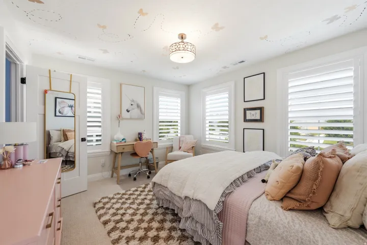 Bright, light-filled bedroom featuring multiple shuttered windows with natural light, neutral wall finishes, and ceiling-mounted lighting fixture