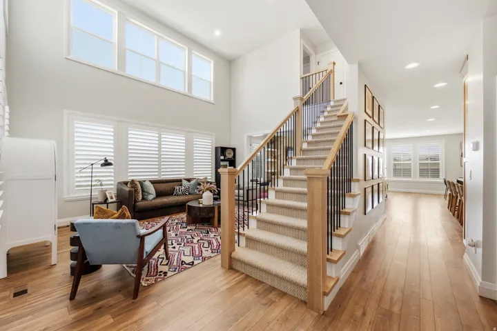 Two-story entry foyer with wood-finish flooring and a carpeted staircase featuring wood handrails and black metal balusters