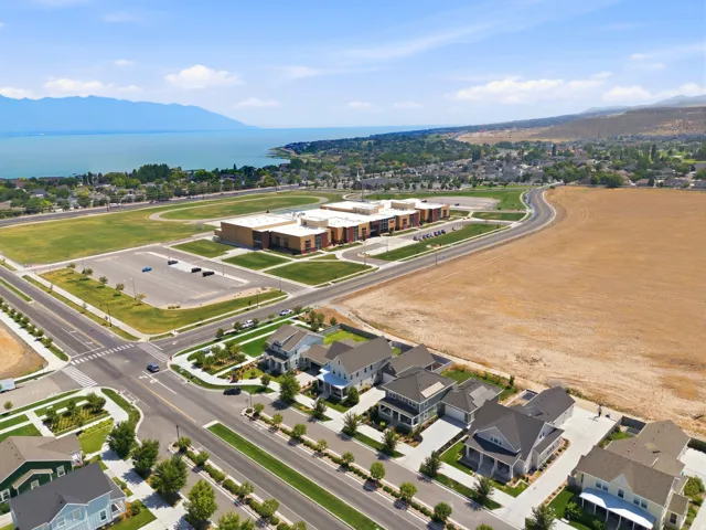 Aerial perspective featuring a residential area with varied architectural styles, manicured lawns, and paved driveways