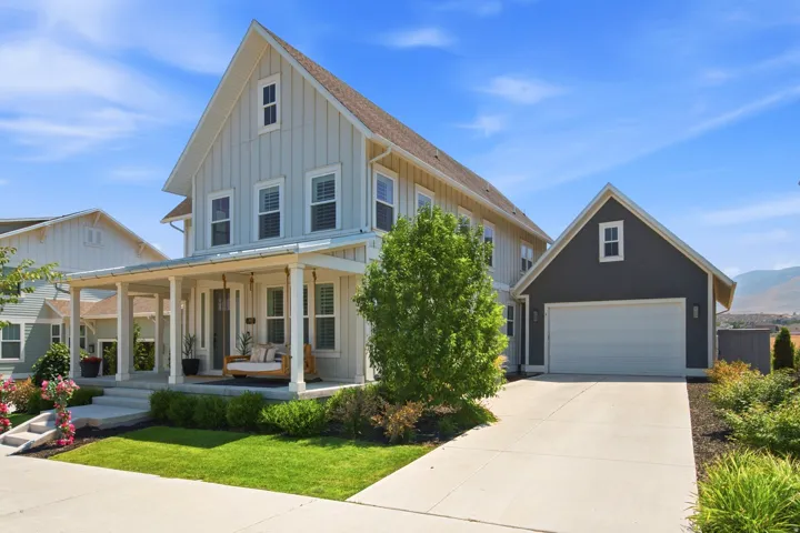 Two-story residence featuring board and batten siding, a covered front porch, and a detached two-car garage with matching dark siding
