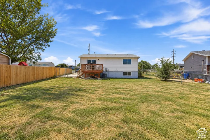 Expansive backyard featuring a wood privacy fence, elevated wooden deck, and open lawn space