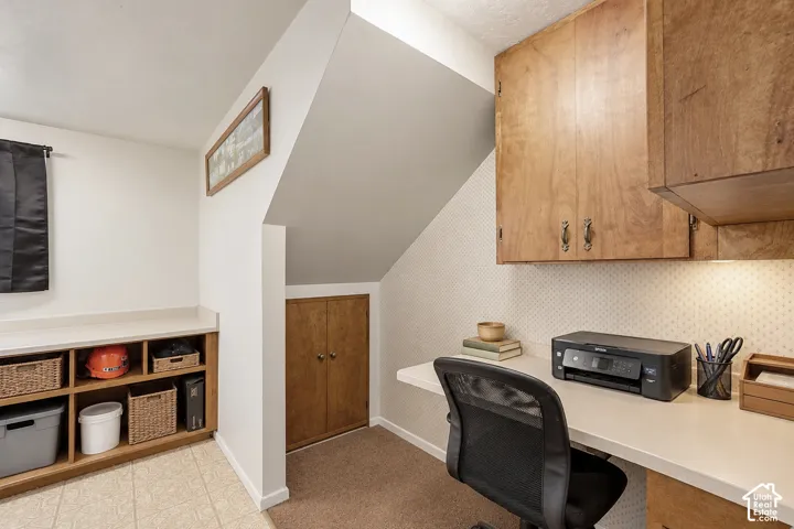 Built-in workspace featuring wood-finish cabinetry, solid surface countertop, and additional under-stair storage