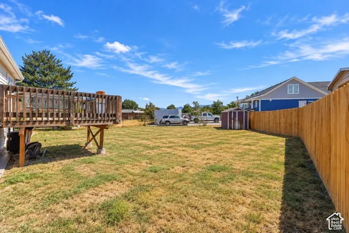 Expansive backyard featuring a wood deck, perimeter wood fencing, and a detached storage shed