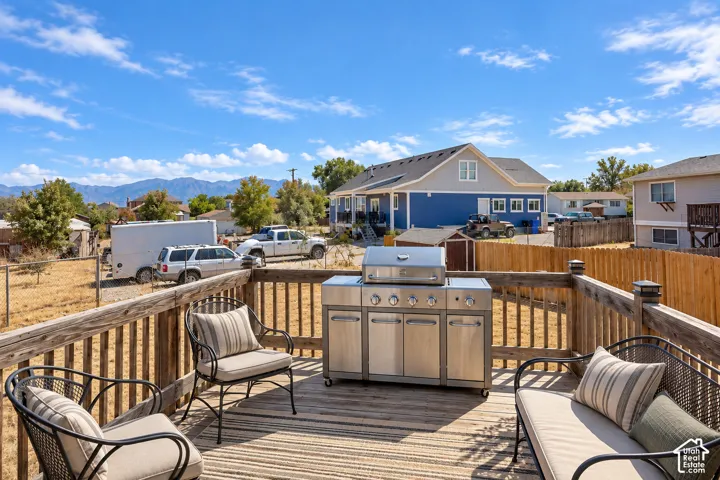 Elevated wood deck featuring a wooden perimeter railing with built-in post lighting and expansive mountain backdrop