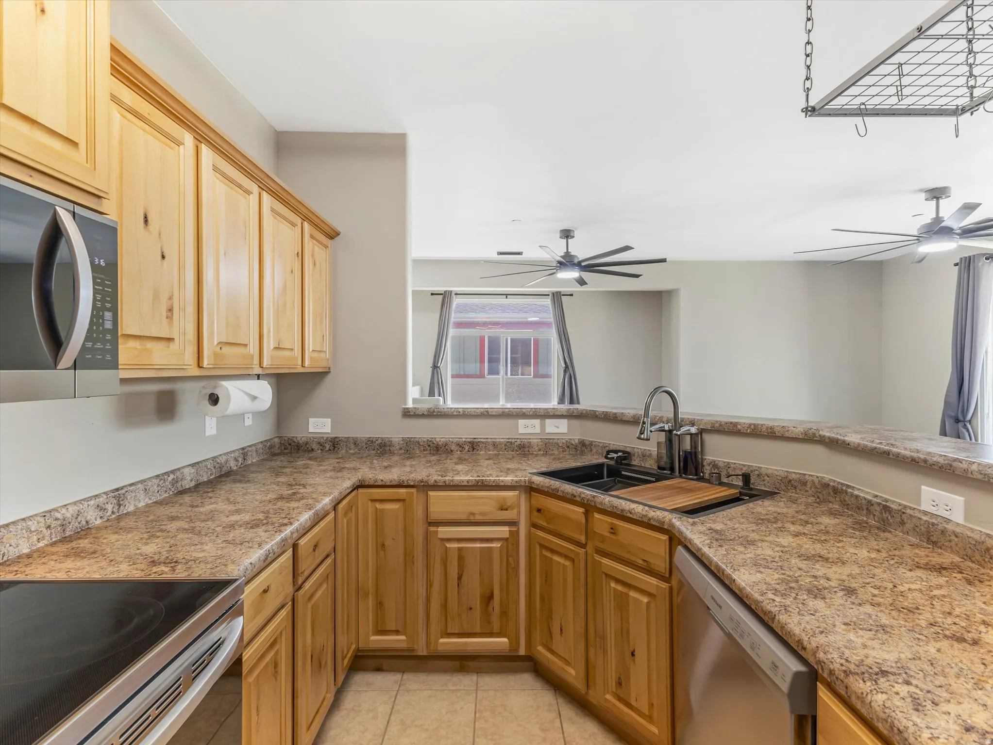 Kitchen featuring light wood cabinetry, stone-look countertops, and stainless steel appliances