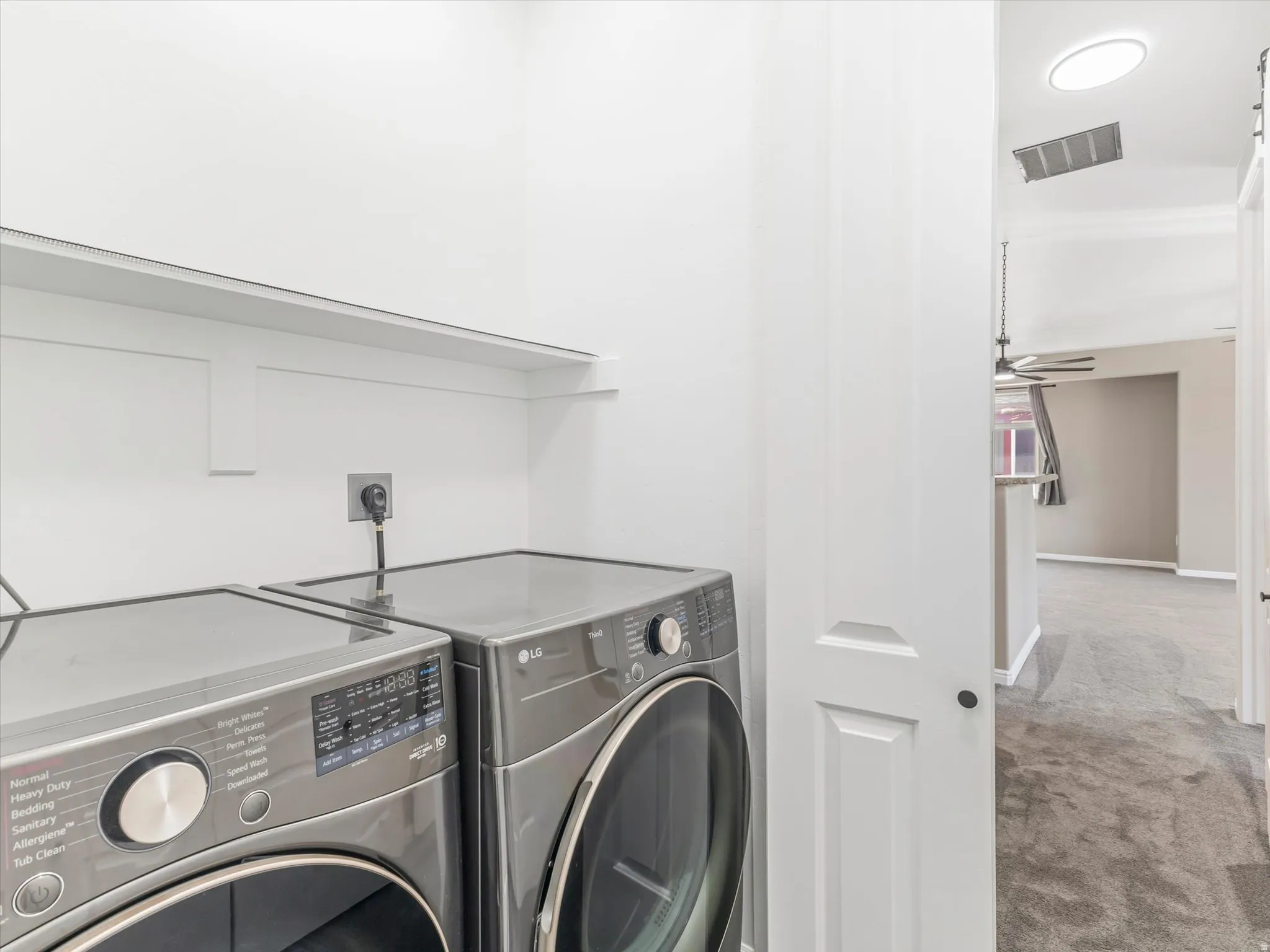 Dedicated laundry area with built-in shelving, white walls, and a white paneled door