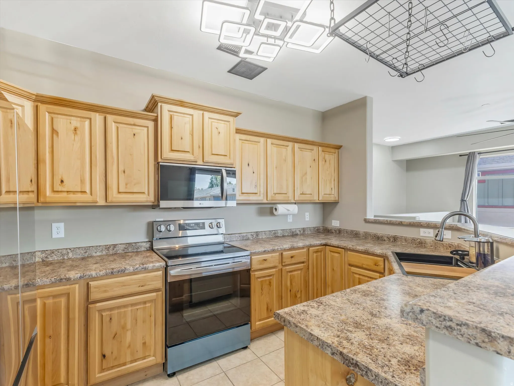 Kitchen featuring wood cabinetry, stainless steel microwave, stainless steel electric range, and composite countertops
