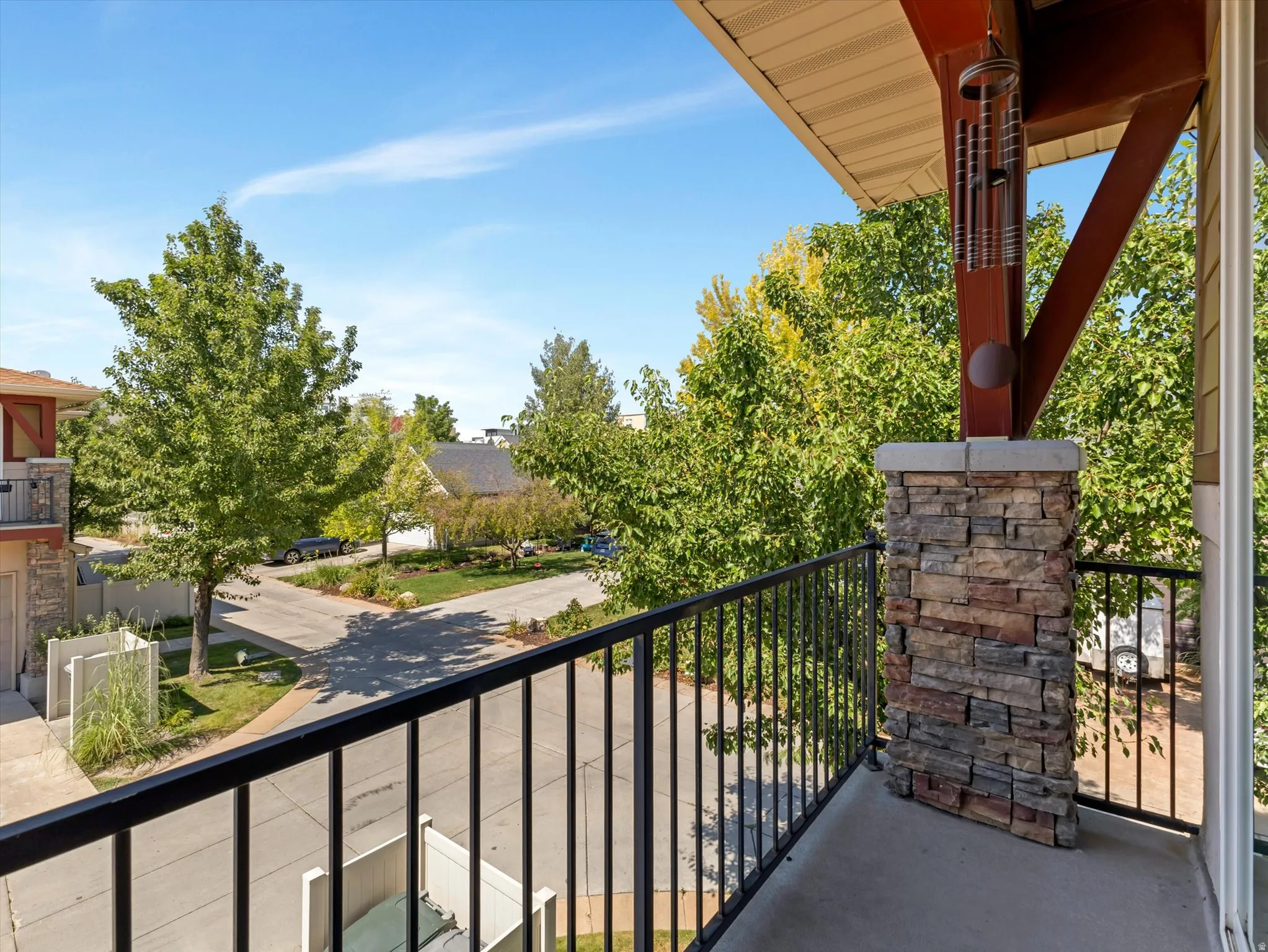 Balcony featuring a concrete surface, black metal railing, and a stone-clad support pillar