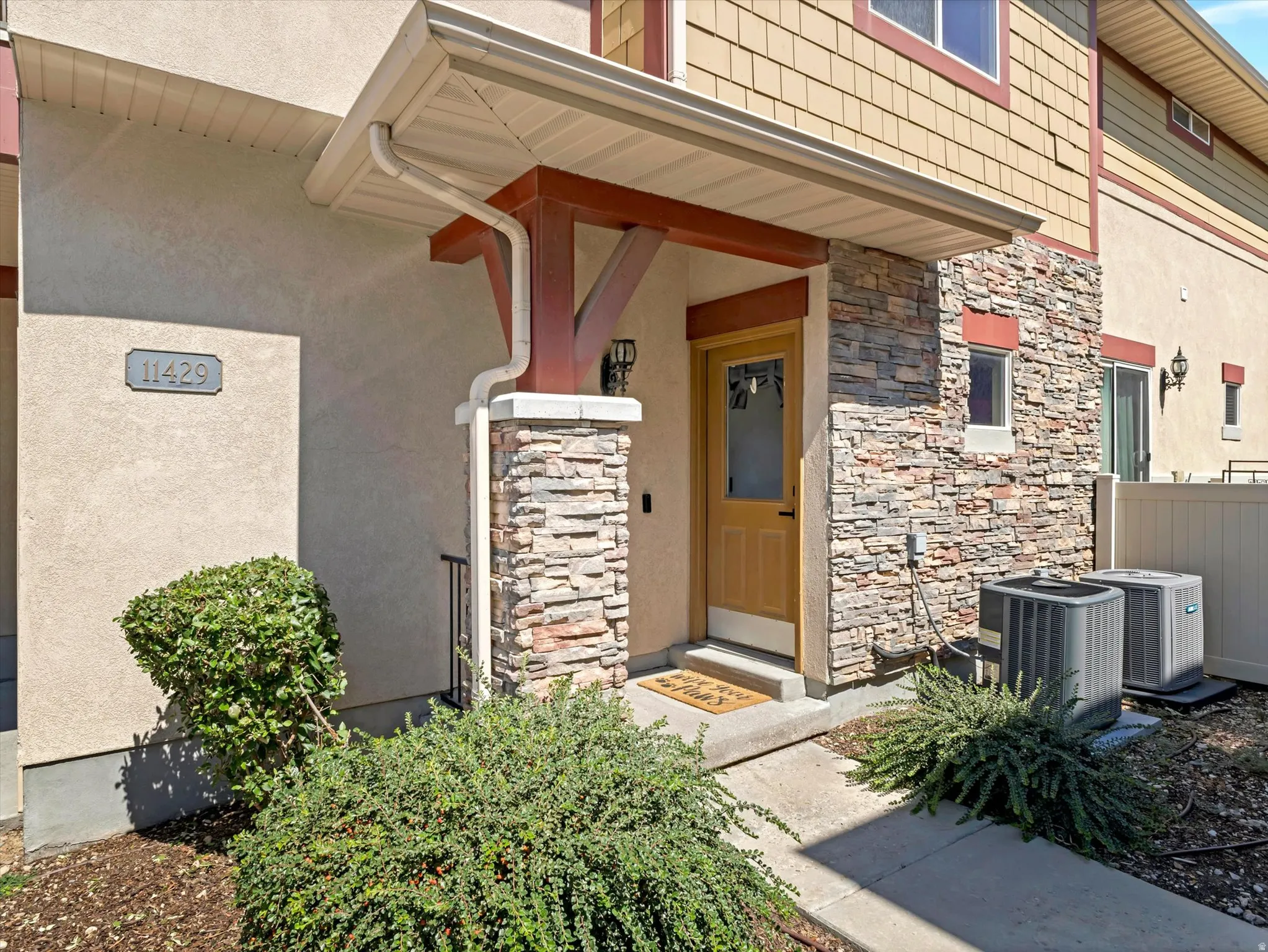 Entryway featuring a wood paneled door, stone facade, and a covered porch