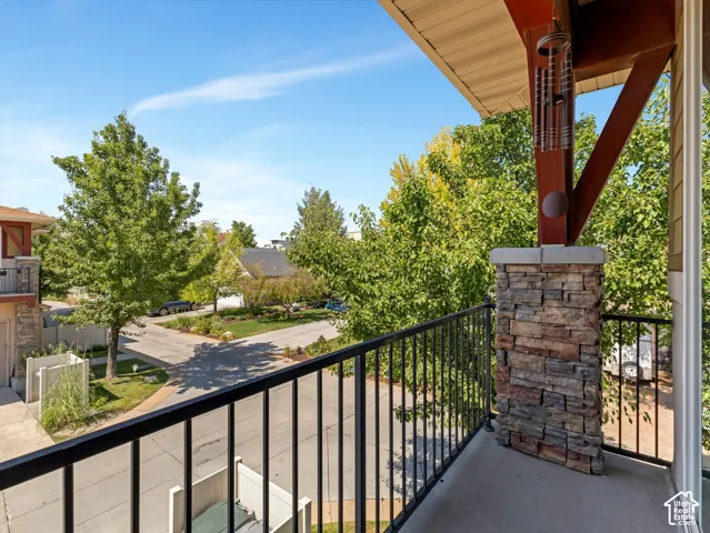 Balcony featuring a concrete surface, black metal railing, and a stone-clad support pillar