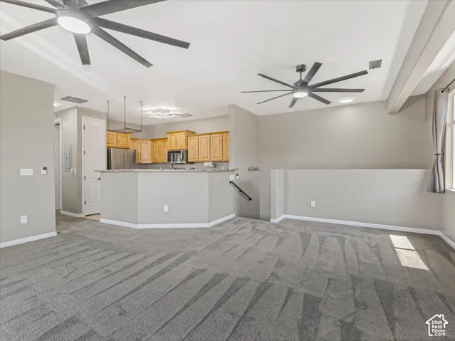 Open-concept living area with gray carpeting and two contemporary ceiling fans