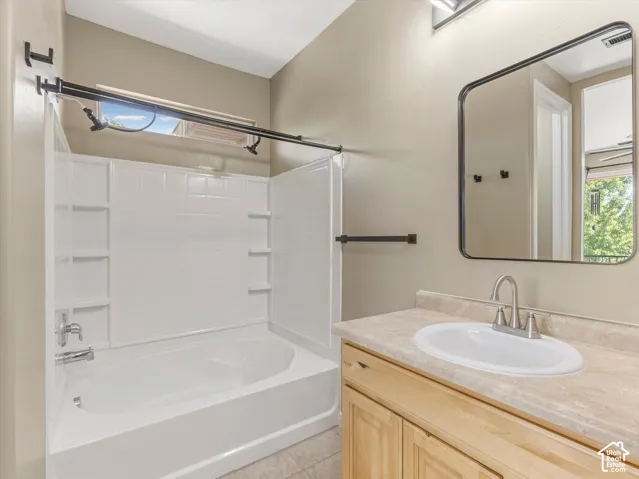 Bathroom featuring a single vanity with an oval sink, brushed nickel faucet, and natural wood-finish cabinetry